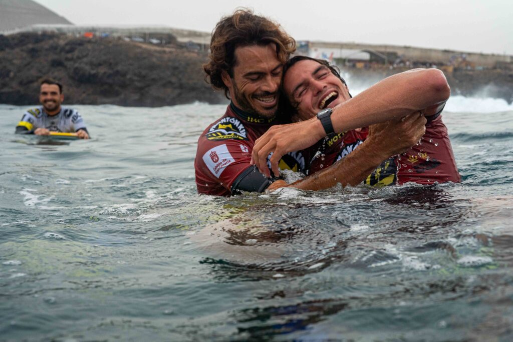 Pierre-Louis Costes y Tristan Roberts se abrazan en el agua de El Frontón (Gáldar)